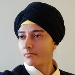 Amardeep Kaur, looking out to the side of the camera, wearing a black and white shirt.