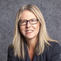 Brenda Cossman, smiling at the camera, wearing a fancy grey shirt, with glasses on.