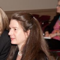 Sideshot of Jenny Purtle wearing a black sweater, grey shirt, and white necklace.