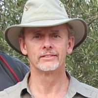 Ted Banning, wearing a safari hat and shirt, looking at the camera.