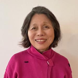 Judge Omatsu smiles for the camera. She is wearing her dark hair in a long bob and a pink jacket.