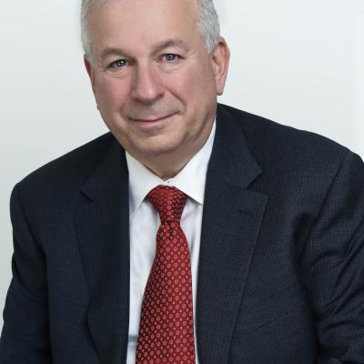 Portrait of David Rosenberg in a black suit, white shirt and crimson tie